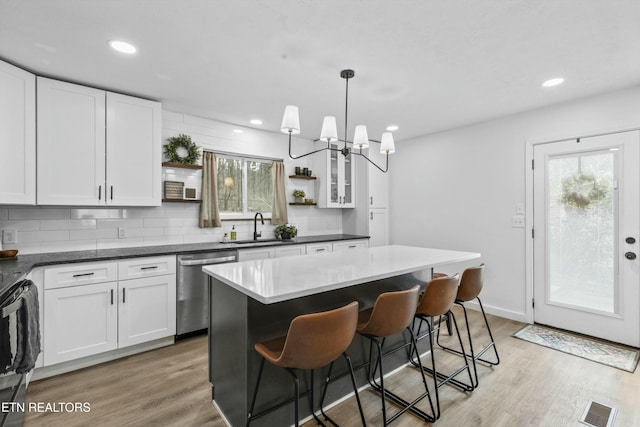 kitchen featuring visible vents, dishwasher, light wood-style flooring, open shelves, and a sink