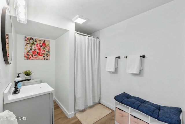 bathroom with curtained shower, baseboards, wood finished floors, and vanity