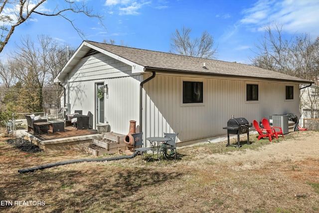 back of house with roof with shingles and a deck