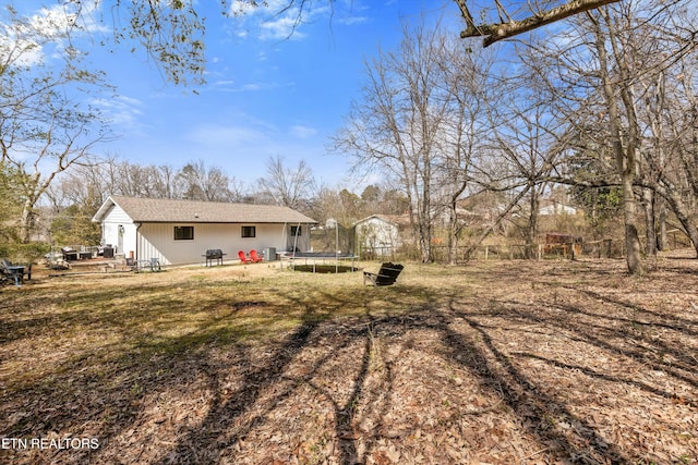 rear view of property featuring entry steps, a trampoline, and a lawn