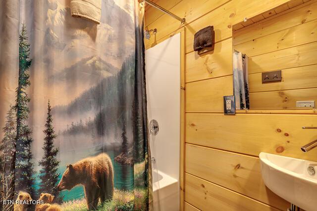 1012 Ravens Ford Way, Sevierville, TN 37876 - bathroom with a sink, wooden walls, and shower / bath combo with shower curtain