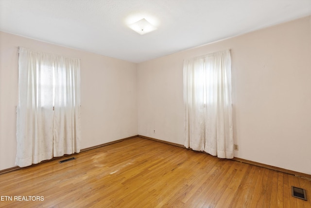 empty room with light wood-type flooring and visible vents