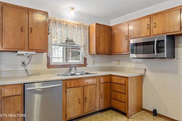 kitchen with light floors, stainless steel appliances, light countertops, backsplash, and a sink