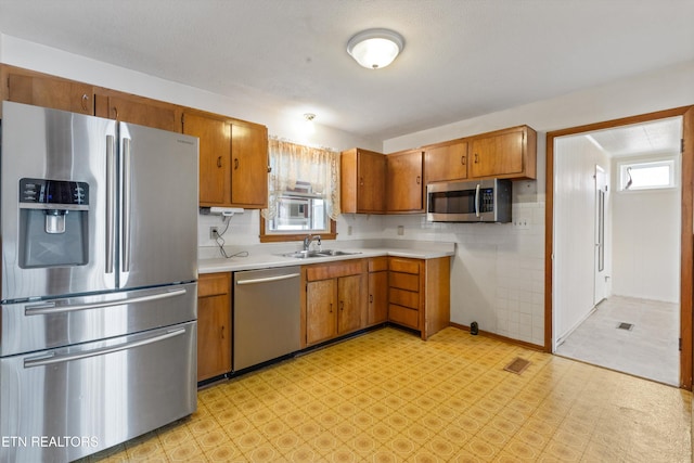 kitchen with light floors, appliances with stainless steel finishes, a wealth of natural light, and a sink