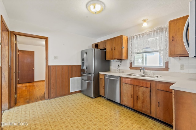 kitchen featuring visible vents, a wainscoted wall, appliances with stainless steel finishes, light countertops, and a sink