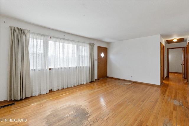 spare room with hardwood / wood-style flooring, baseboards, and visible vents