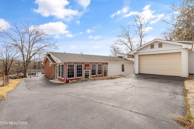 view of front of property with driveway, a garage, a sunroom, an outdoor structure, and brick siding