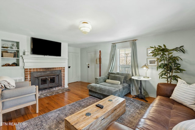 living room with baseboards, visible vents, wood finished floors, built in shelves, and a fireplace