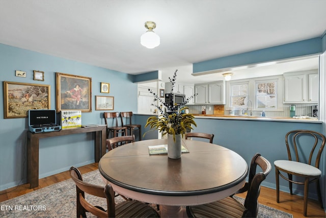 dining space with baseboards and wood finished floors