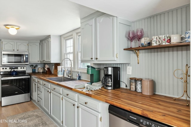 kitchen with light wood-style flooring, appliances with stainless steel finishes, wooden counters, and a sink