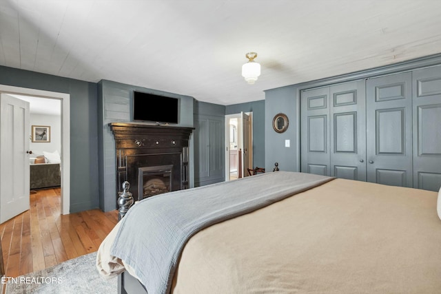 bedroom featuring a glass covered fireplace, a closet, and hardwood / wood-style floors