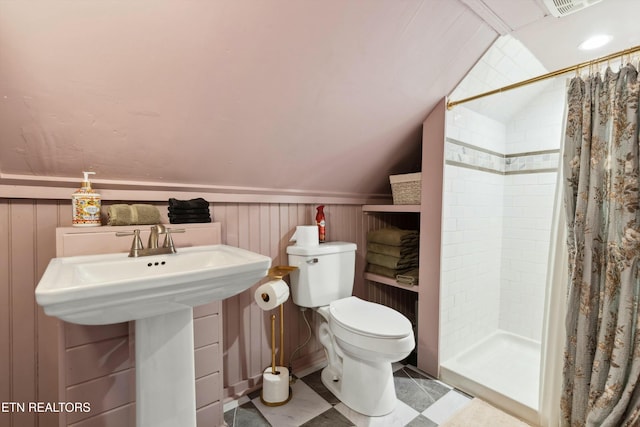 bathroom featuring a stall shower, wainscoting, toilet, lofted ceiling, and a sink