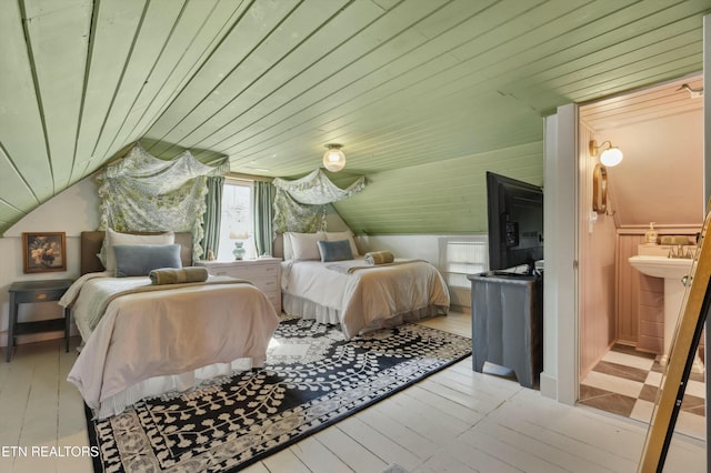 bedroom with light wood-style floors, wooden ceiling, vaulted ceiling, and ensuite bath