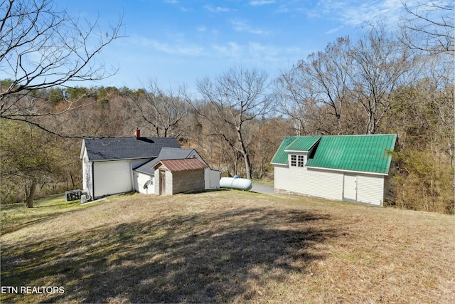 view of side of home with an outbuilding, metal roof, and a yard