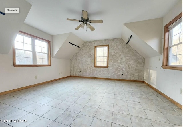 bonus room featuring lofted ceiling, a healthy amount of sunlight, and baseboards