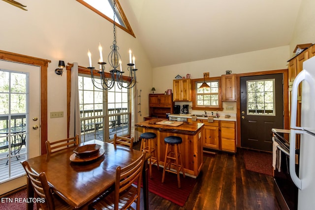 dining area featuring high vaulted ceiling, dark wood-style flooring, a wealth of natural light, and an inviting chandelier