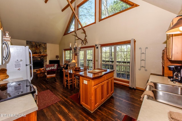 kitchen with a stone fireplace, a sink, freestanding refrigerator, brown cabinetry, and dark wood finished floors