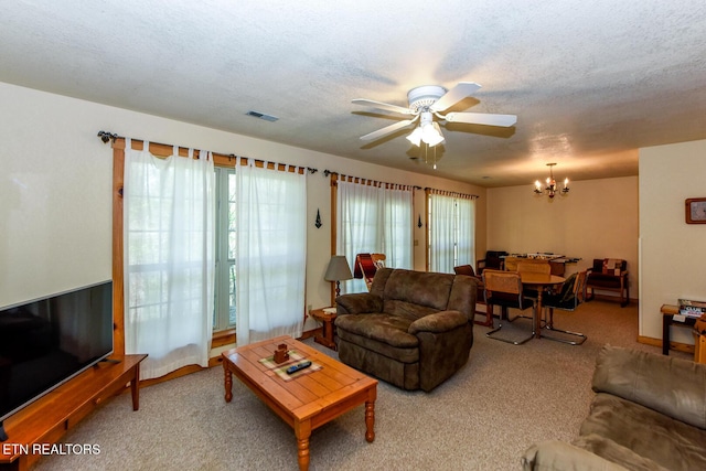 living area featuring carpet, visible vents, a textured ceiling, and ceiling fan with notable chandelier