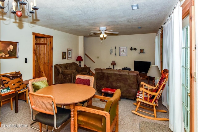 carpeted dining space featuring a textured ceiling and ceiling fan with notable chandelier