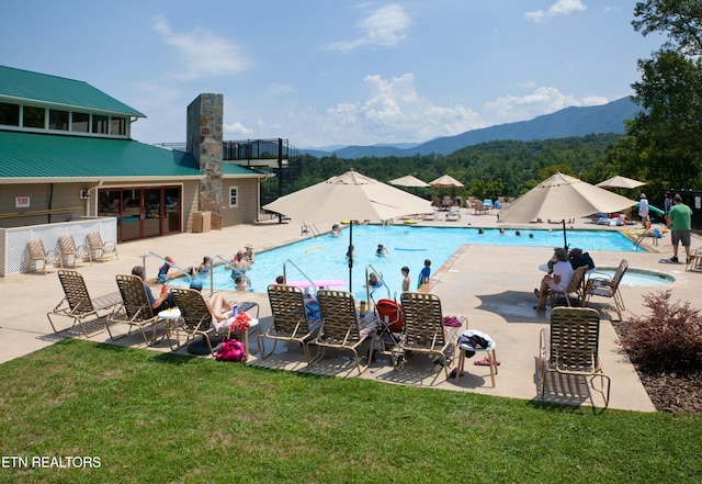 community pool featuring a yard, a patio, fence, and a mountain view