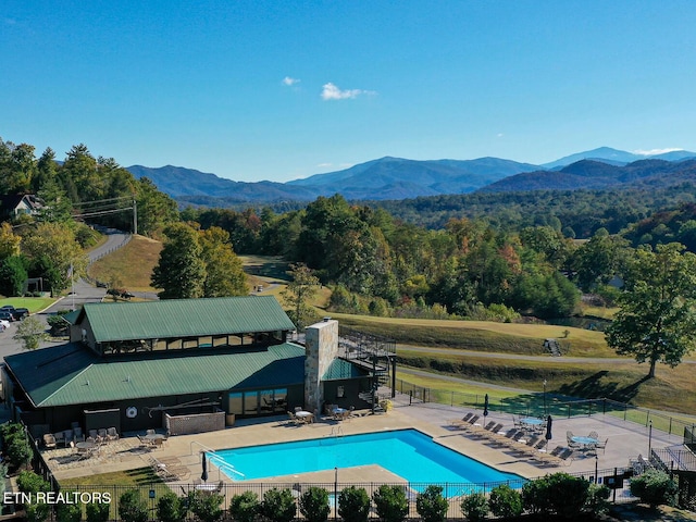 community pool featuring fence, a mountain view, and a patio