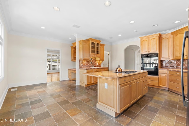 kitchen featuring baseboards, ornamental molding, a center island, stainless steel gas cooktop, and backsplash