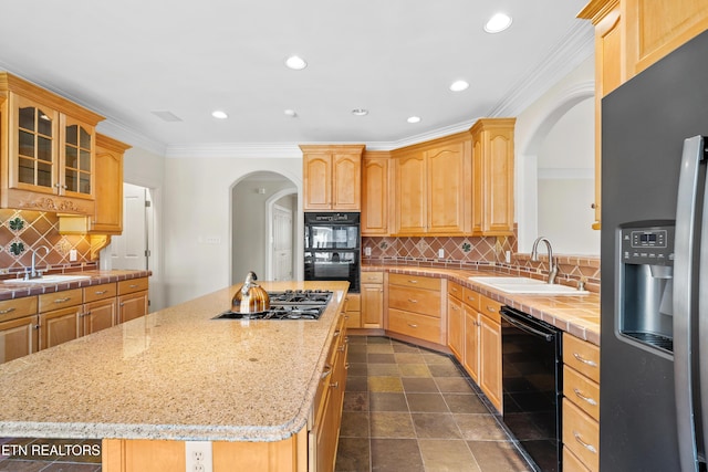 kitchen with black appliances, a kitchen island, ornamental molding, and a sink