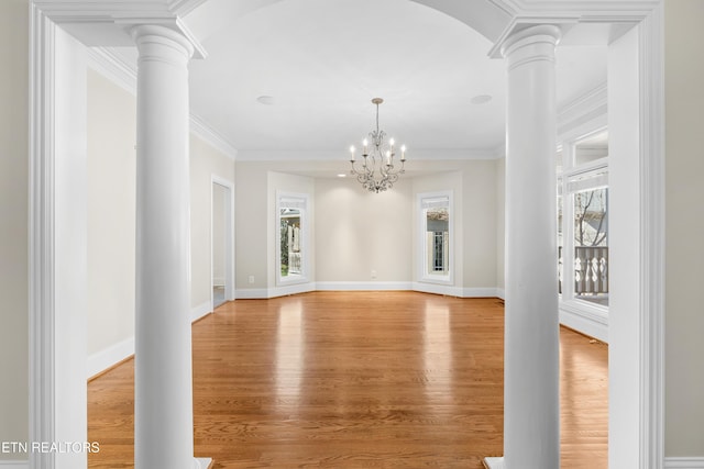 unfurnished room featuring light wood-style floors, crown molding, and ornate columns