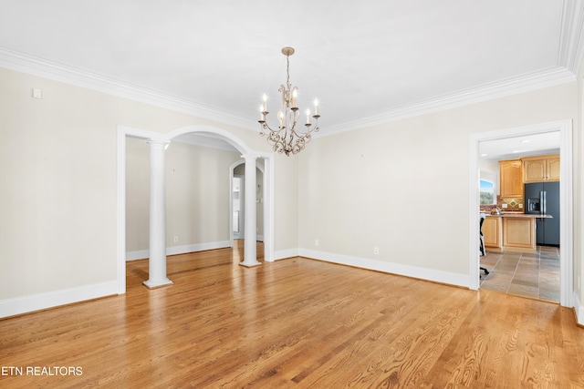 unfurnished dining area featuring arched walkways, crown molding, light wood-style flooring, and ornate columns