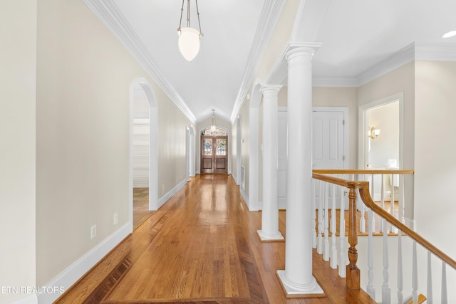 corridor featuring ornamental molding, decorative columns, and wood finished floors