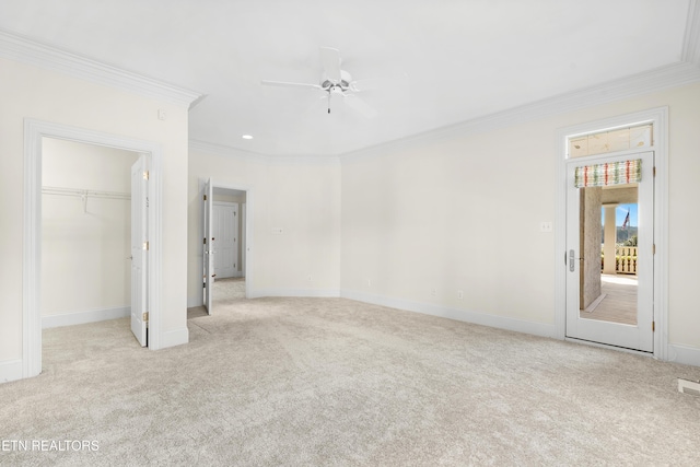 unfurnished bedroom featuring carpet, baseboards, a walk in closet, and crown molding