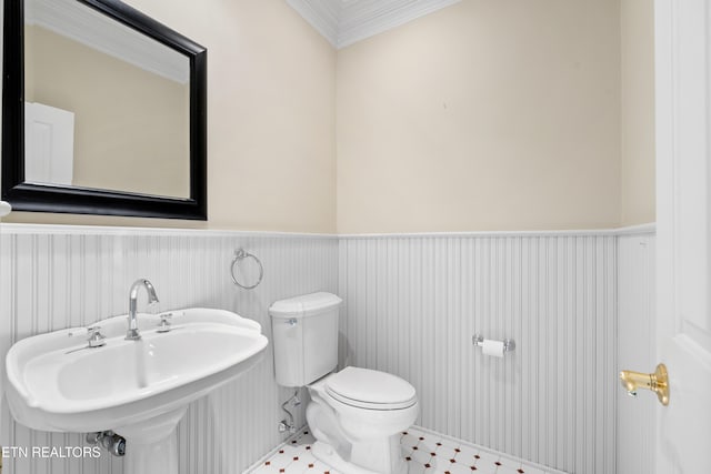 bathroom with toilet, a sink, and wainscoting