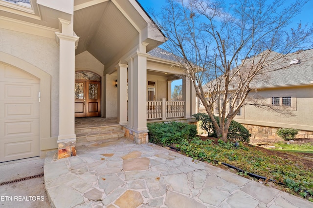 view of exterior entry featuring covered porch, a shingled roof, an attached garage, and stucco siding