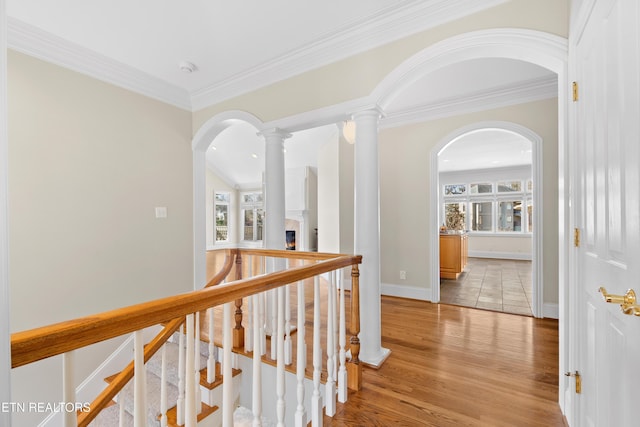 corridor with ornamental molding, baseboards, light wood-style flooring, and ornate columns