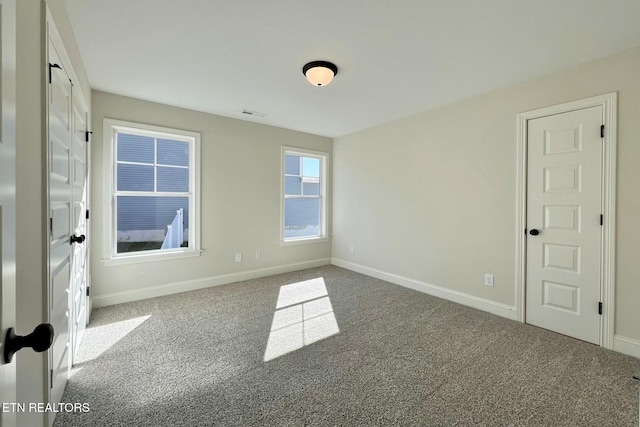 carpeted spare room with visible vents and baseboards