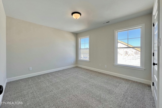 empty room with carpet flooring, visible vents, and baseboards