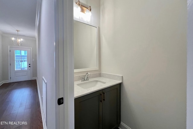 bathroom with baseboards, ornamental molding, wood finished floors, and vanity