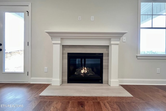 interior details with baseboards, wood finished floors, and a glass covered fireplace