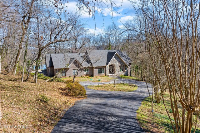 view of front of property with aphalt driveway, stone siding, and a chimney