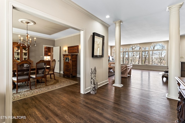 interior space featuring crown molding, baseboards, an inviting chandelier, wood finished floors, and ornate columns