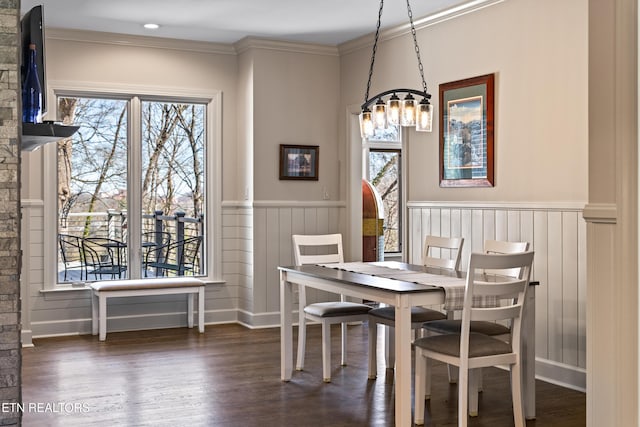 dining area with a wainscoted wall, ornamental molding, and wood finished floors