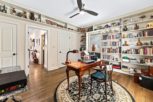 office space featuring dark wood-type flooring, a ceiling fan, baseboards, and ornamental molding