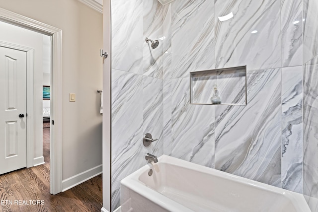 ensuite bathroom with connected bathroom, baseboards, bathing tub / shower combination, and wood finished floors