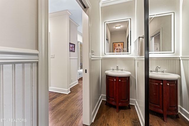 bathroom featuring a sink, two vanities, wood finished floors, and wainscoting