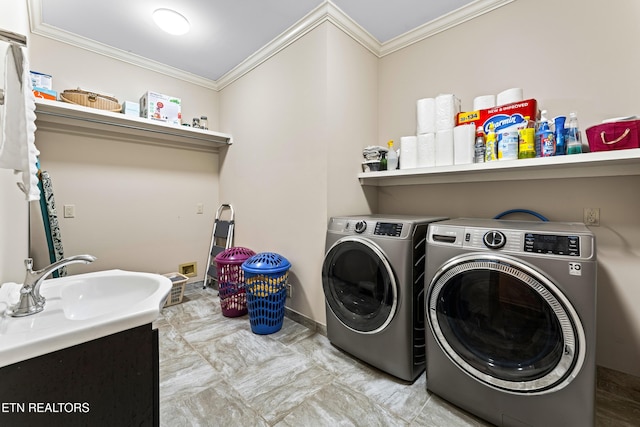 washroom featuring washing machine and clothes dryer, laundry area, crown molding, and a sink