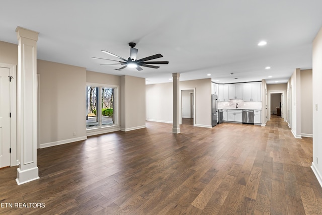 unfurnished living room with dark wood finished floors, recessed lighting, a ceiling fan, and ornate columns