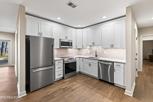 kitchen with tasteful backsplash, dark wood finished floors, light countertops, stainless steel appliances, and a sink