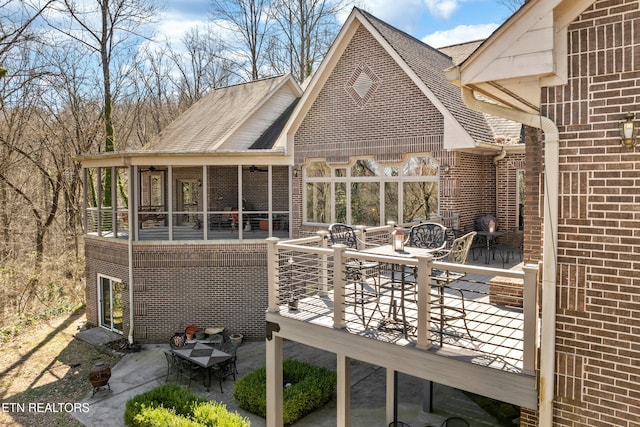 back of house with a patio, brick siding, outdoor dining space, and a sunroom