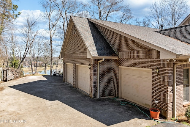 view of home's exterior featuring a detached garage, brick siding, and a shingled roof