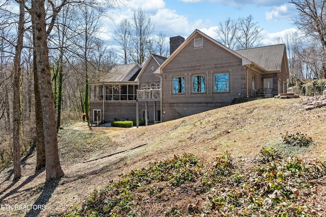 chalet / cabin with brick siding, a chimney, and a sunroom